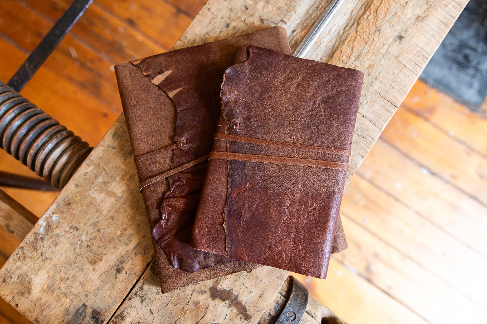 Brown leather notebooks on a rustic wooden surface with metal springs.