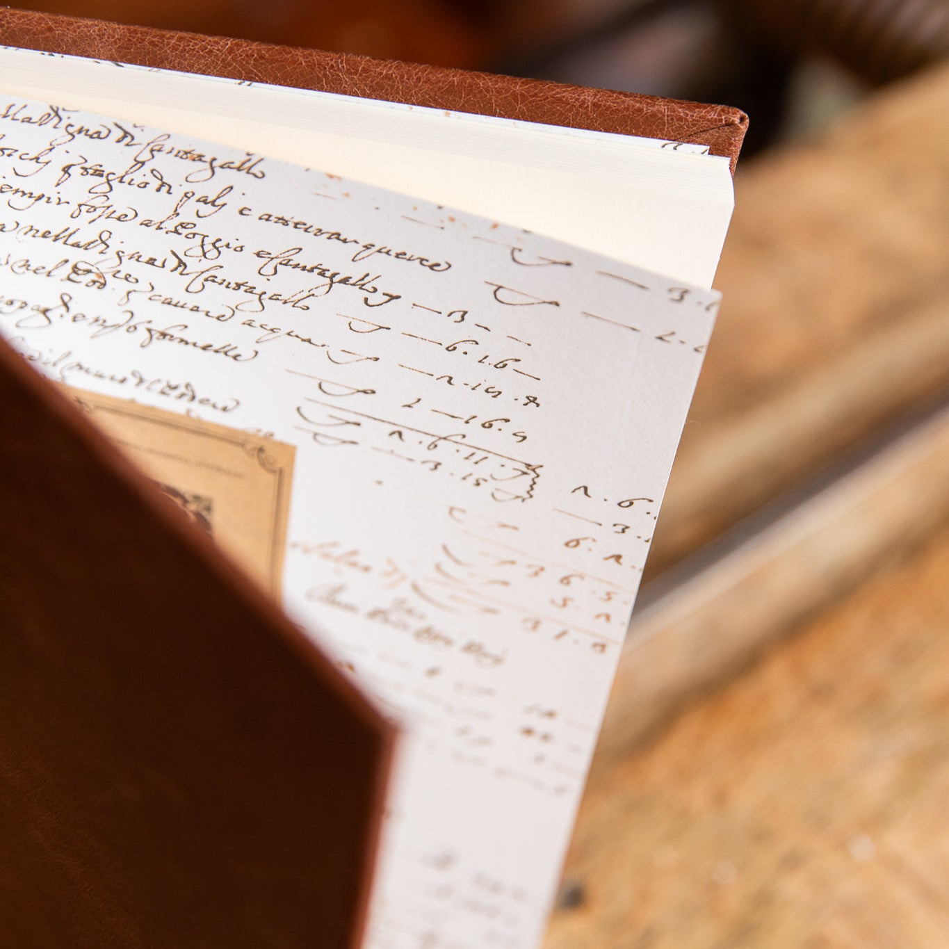 Close-up of an Italian Script endpapers inside leather handcrafted journal resting on a wooden surface.