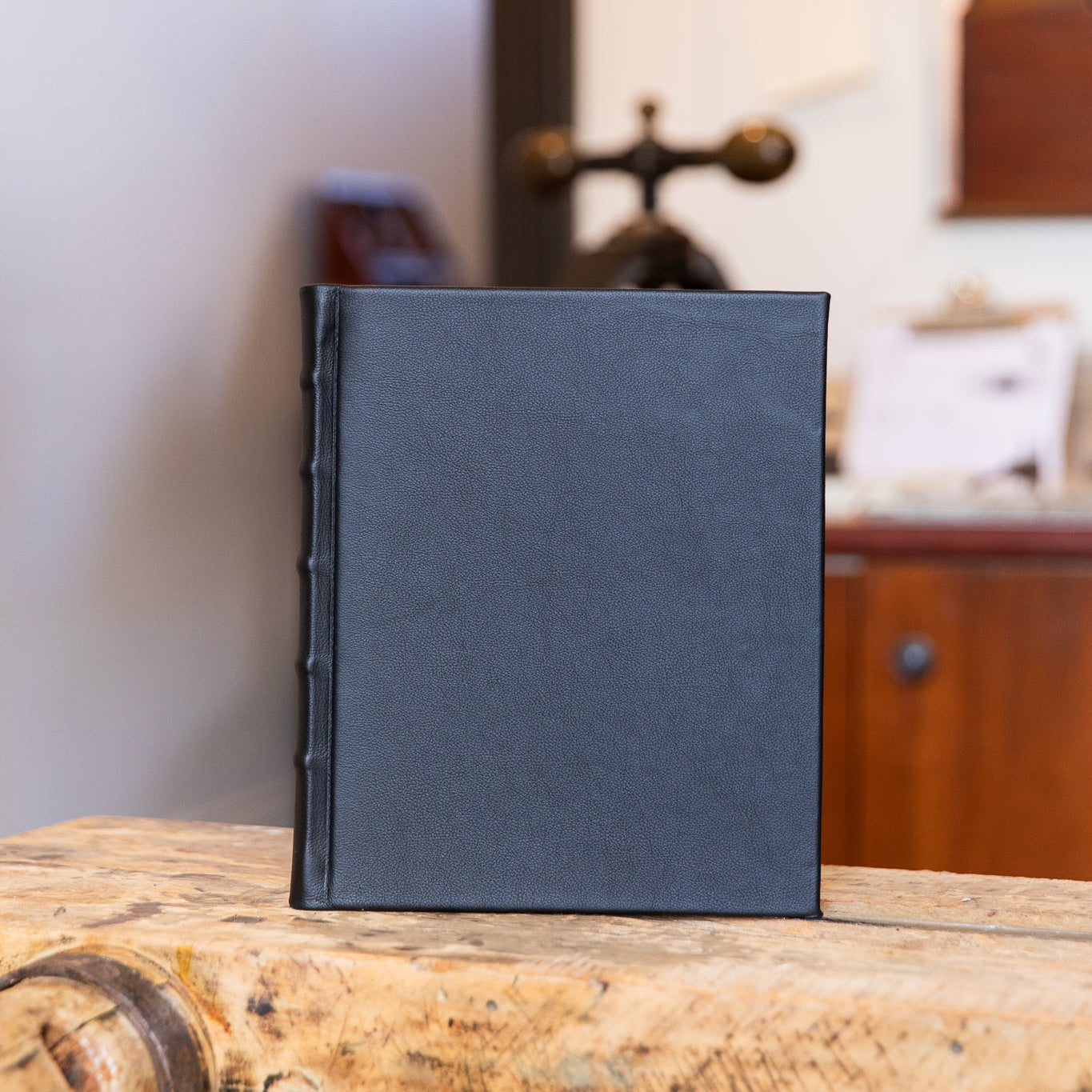 Black leather-bound photo album on a wooden surface with a blurred indoor background