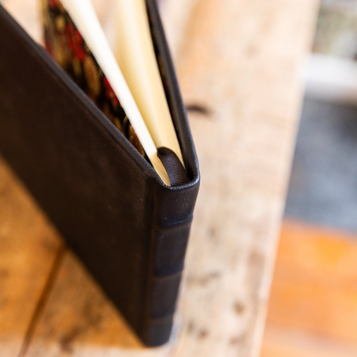 A top view of a black leather guest book with a pen on a wooden surface