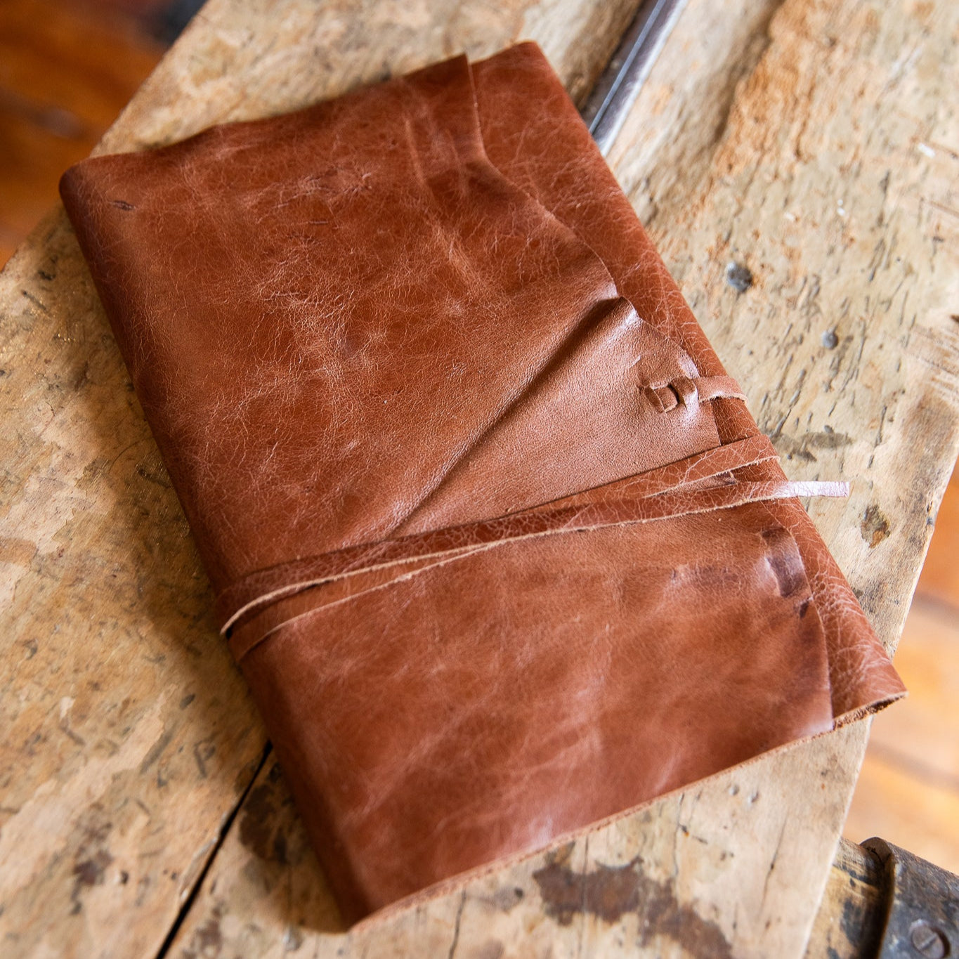 Brown chestnut leather wrap style notebook on a wooden surface