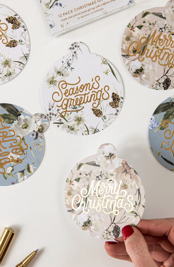 Decorative Christmas gift tags with floral designs and 'Merry Christmas' text on a white surface.