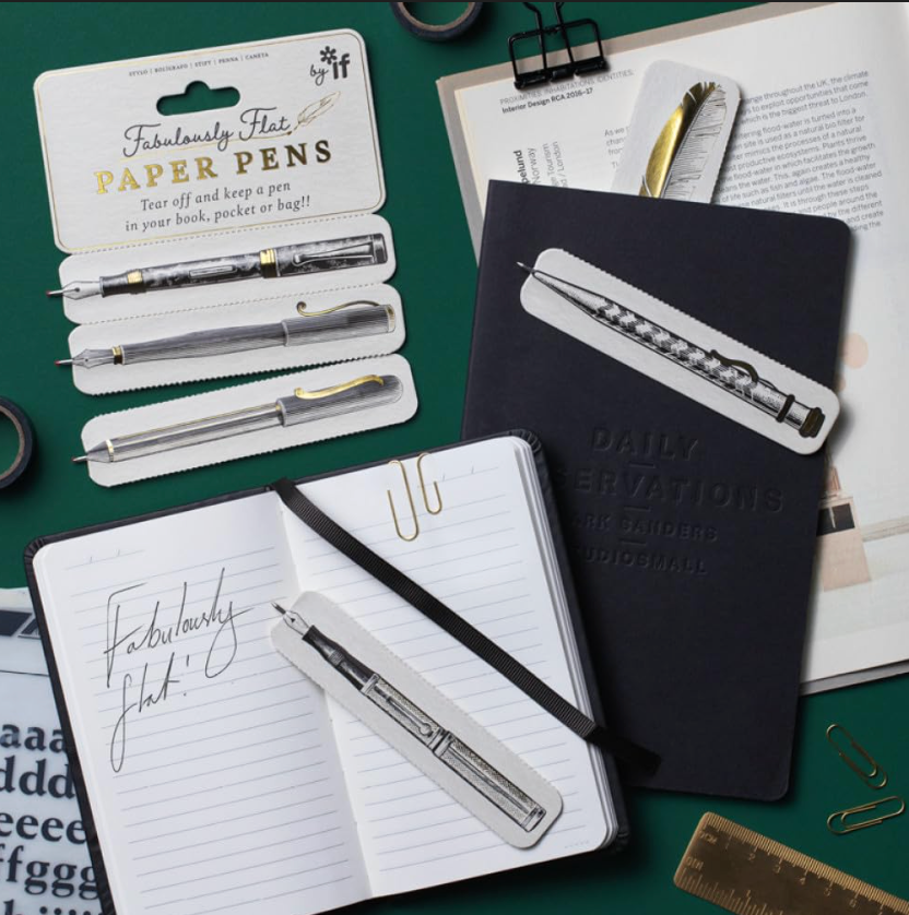 Notebooks and pens on a green surface with stationery items.