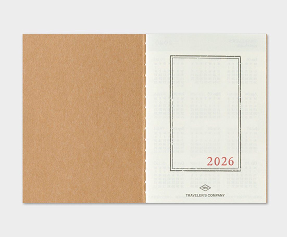 Two notebooks, one brown and one white with '2026' text, on a light gray background.
