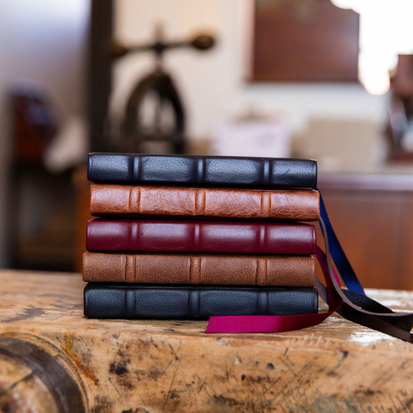 Stack of leather-bound signature books on a wooden surface with a blurred indoor background