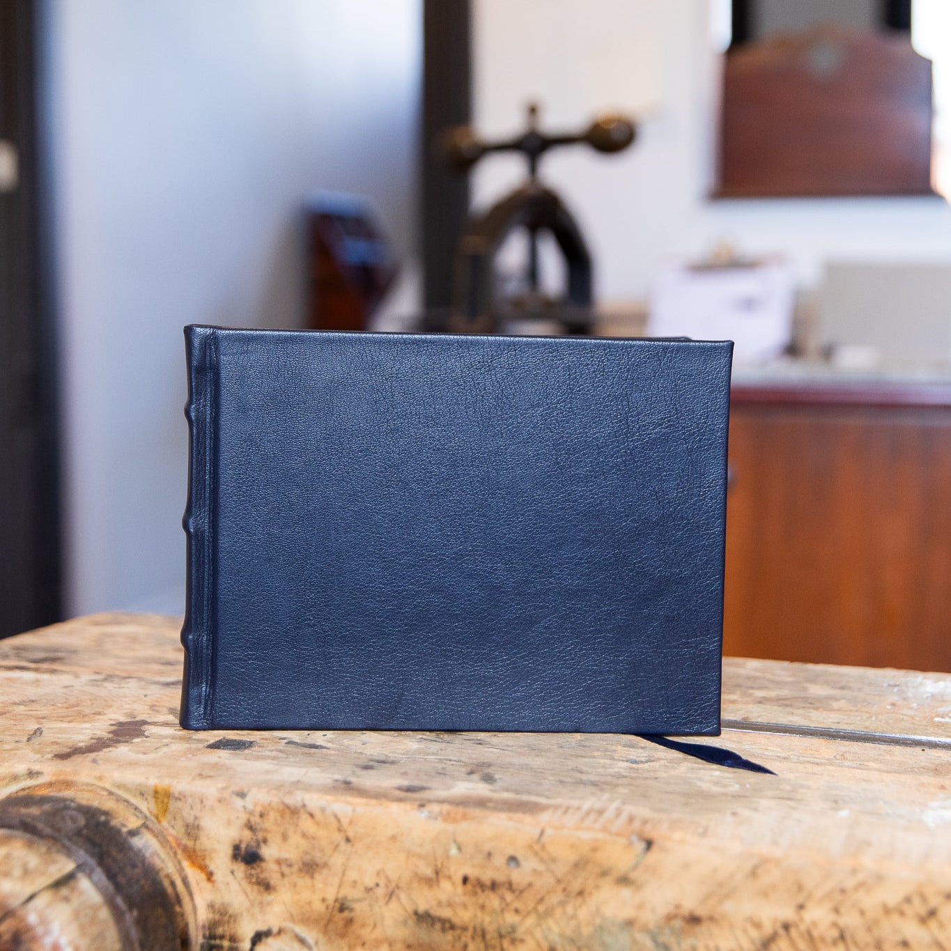 Navy leather-bound guest book on a wooden surface with a blurred indoor background