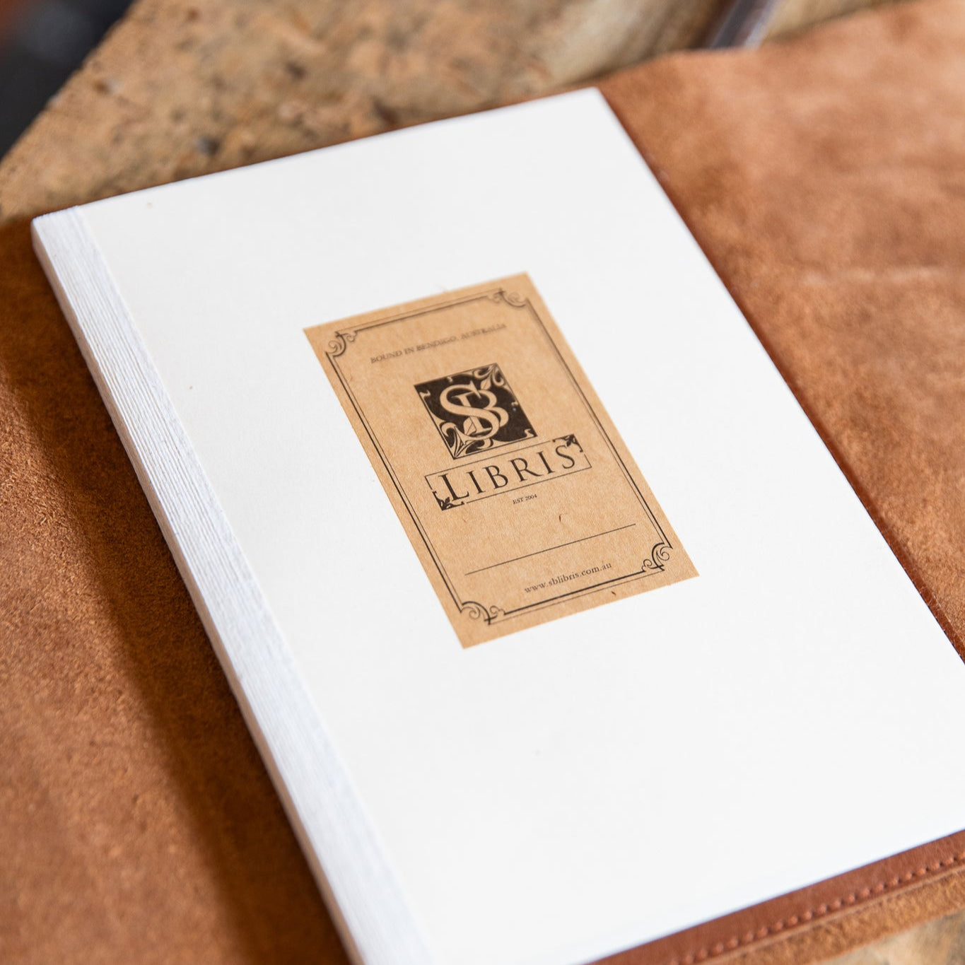 White journal insert with a brown bookplate on a wooden surface