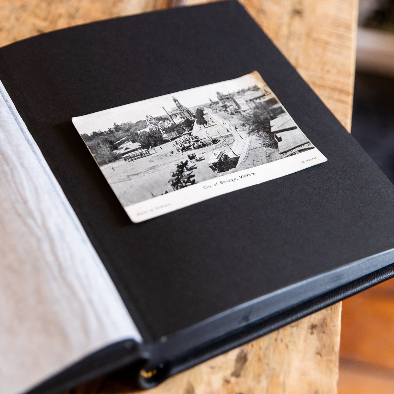 Open black album with a vintage black and white photo on a wooden surface