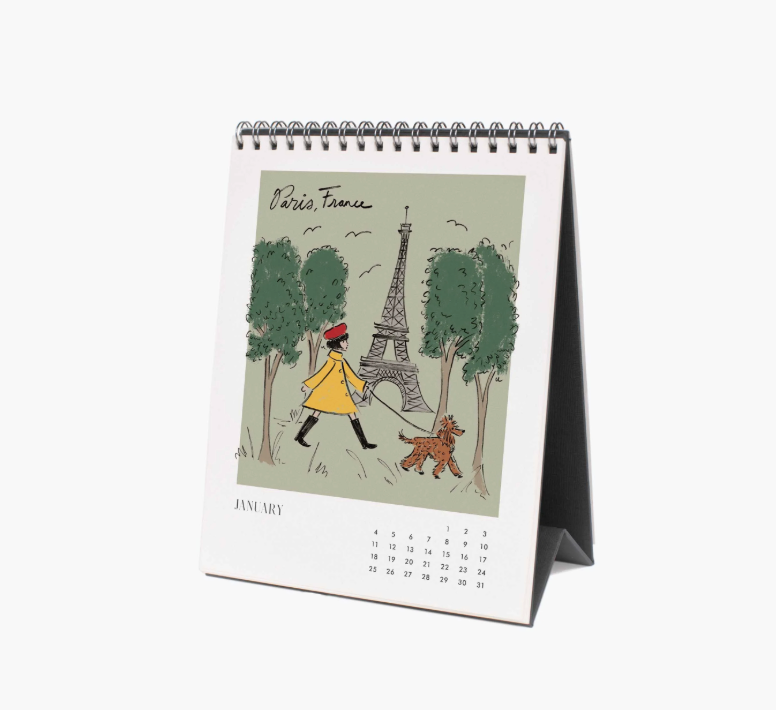 Desk calendar with illustration of a person walking a dog near the Eiffel Tower, on a white background.