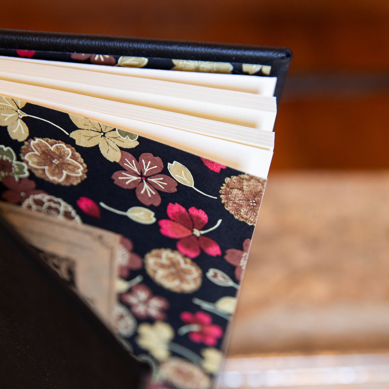 Black Leather Journal with Floral patterned endpapers on a wooden surface