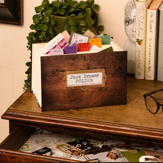 Wooden 'Junk Drawer Folder' on a desk with papers and books in the background