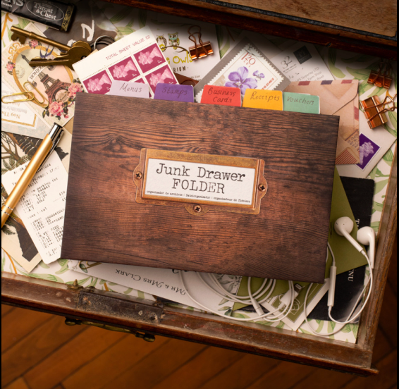 Wooden 'Junk Drawer Folder' on a desk with stationery items.