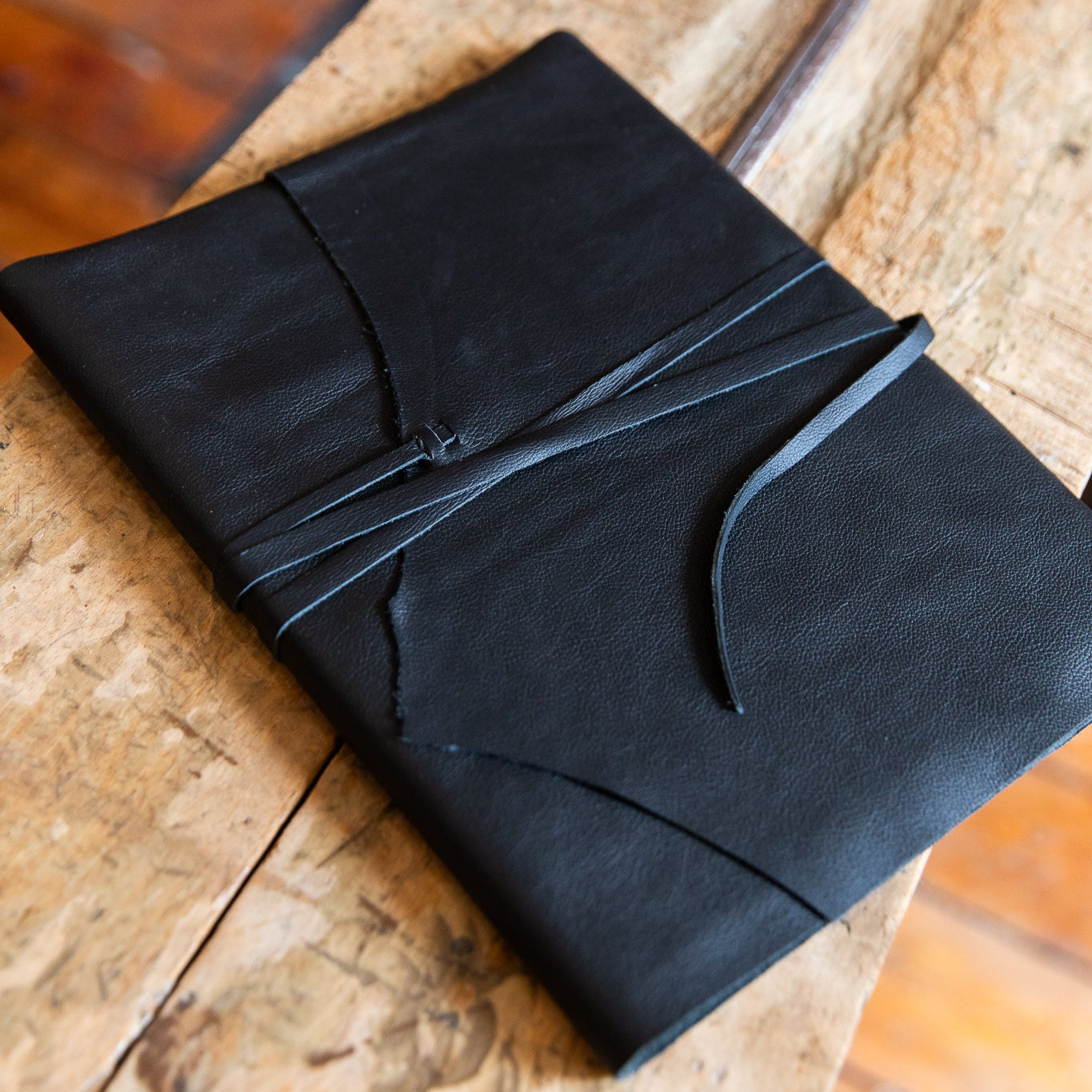 Black large leather wrap journal on a wooden surface