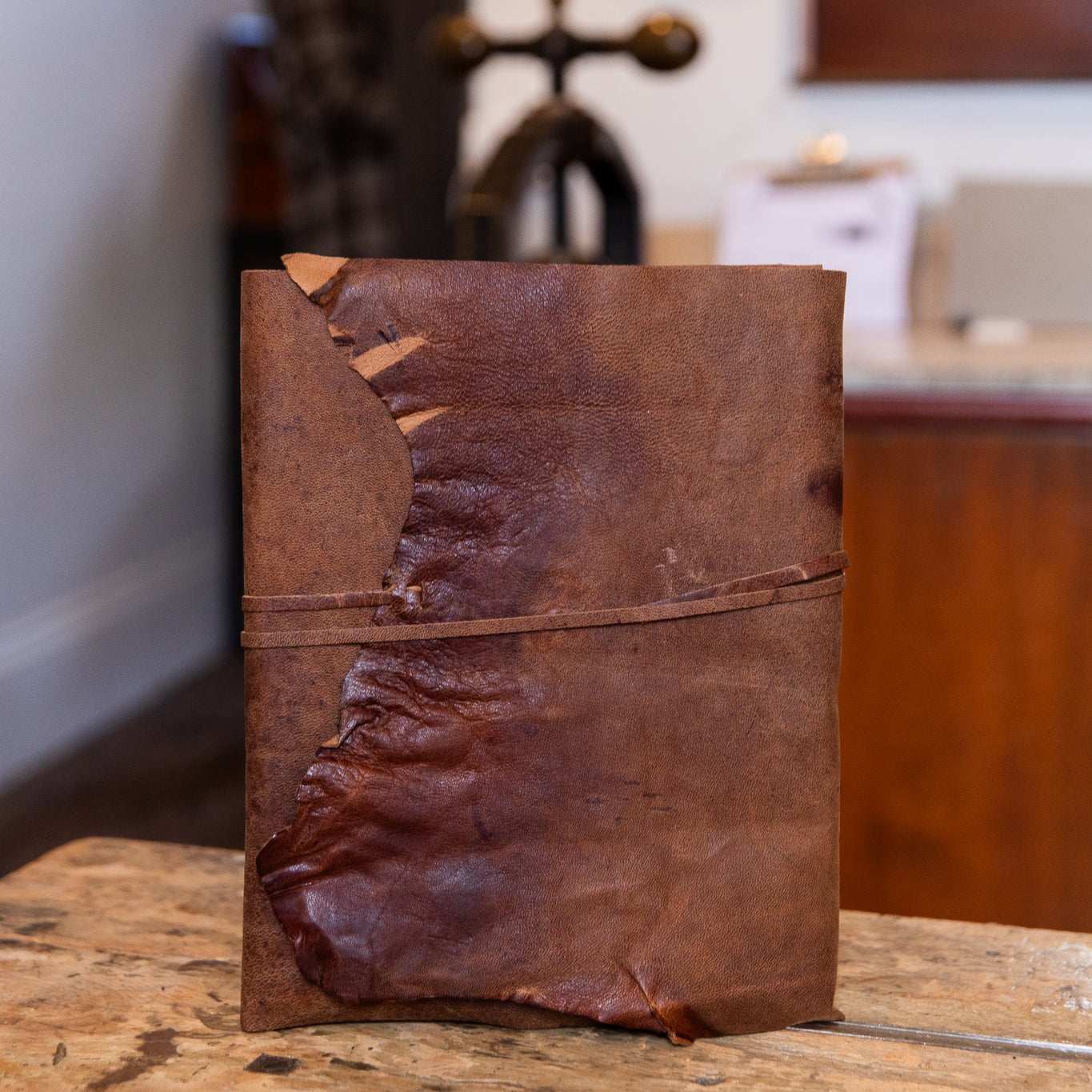 Large leather wrap aged goatskin journal on a wooden surface with a blurred background