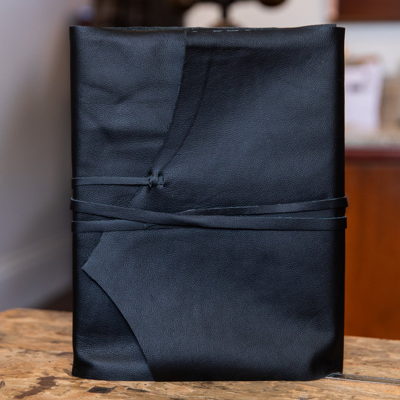Black large leather wrap on a wooden surface with a blurred background