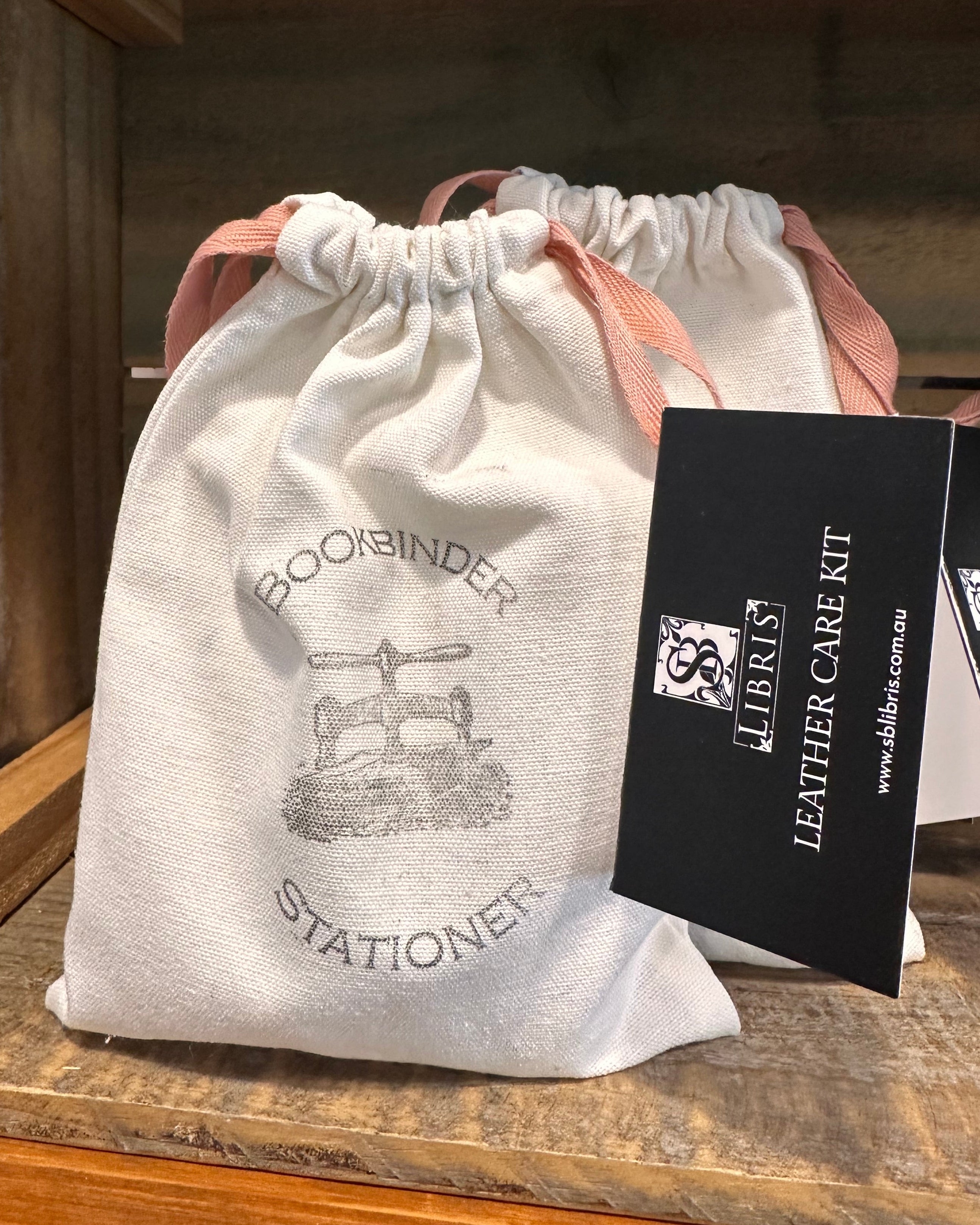 White drawstring bag with branding held against a wooden background