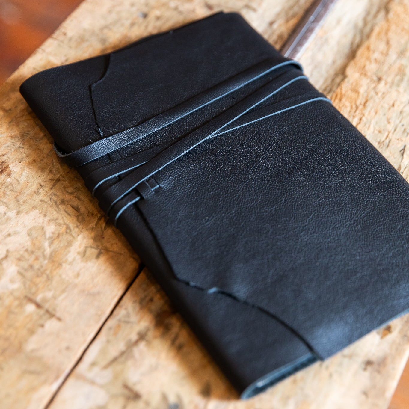 Black leather wrap journal on a wooden surface