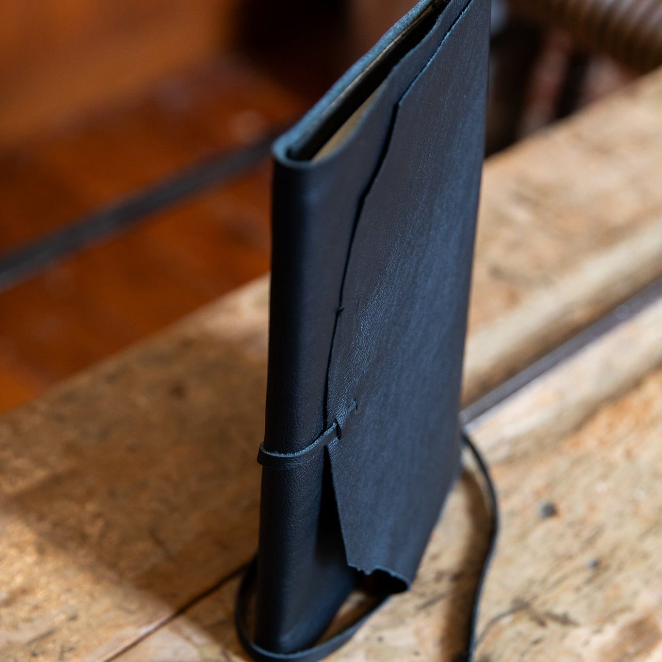 Black leather journal with a strap on a wooden surface