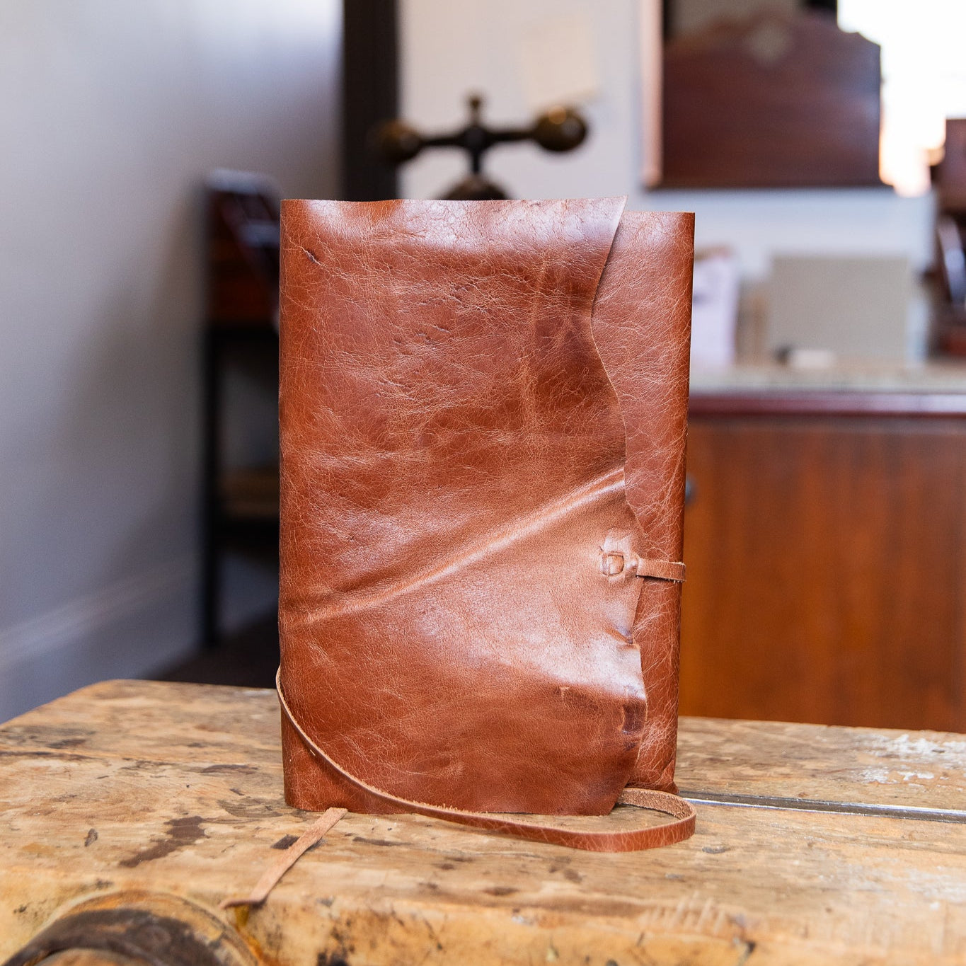 Brown leather wrap journal on a wooden surface with a blurred indoor background