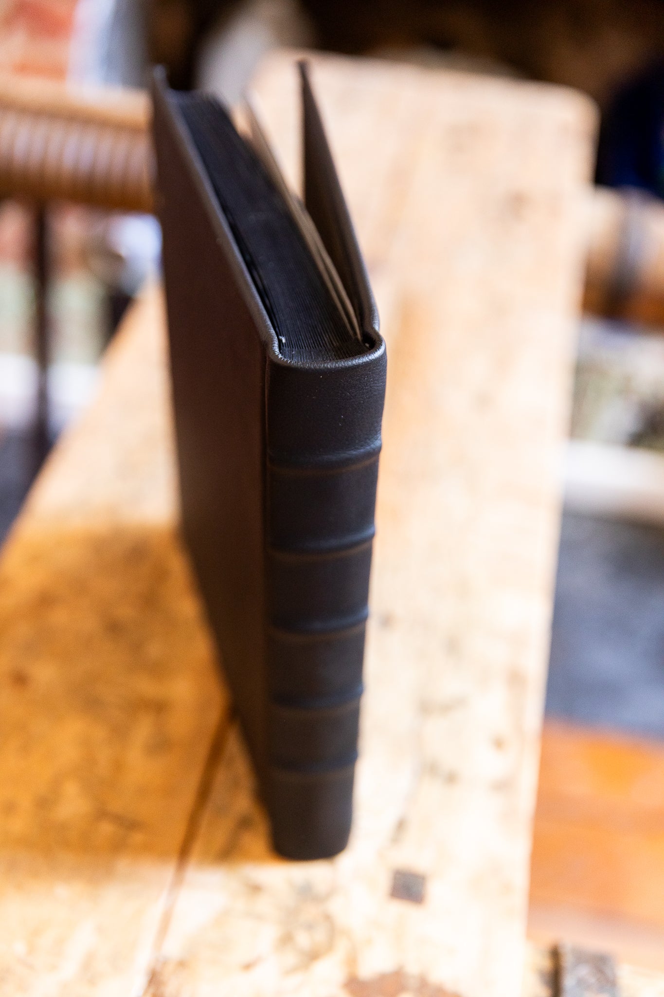 Black leather-bound album from top view on a wooden surface with blurred background