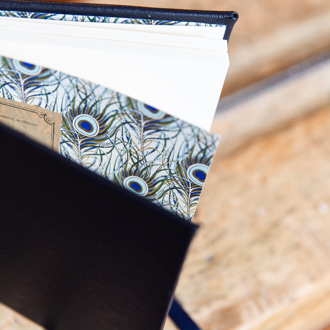 Close-up of a endpapers with peacock feather pattern on a wooden surface