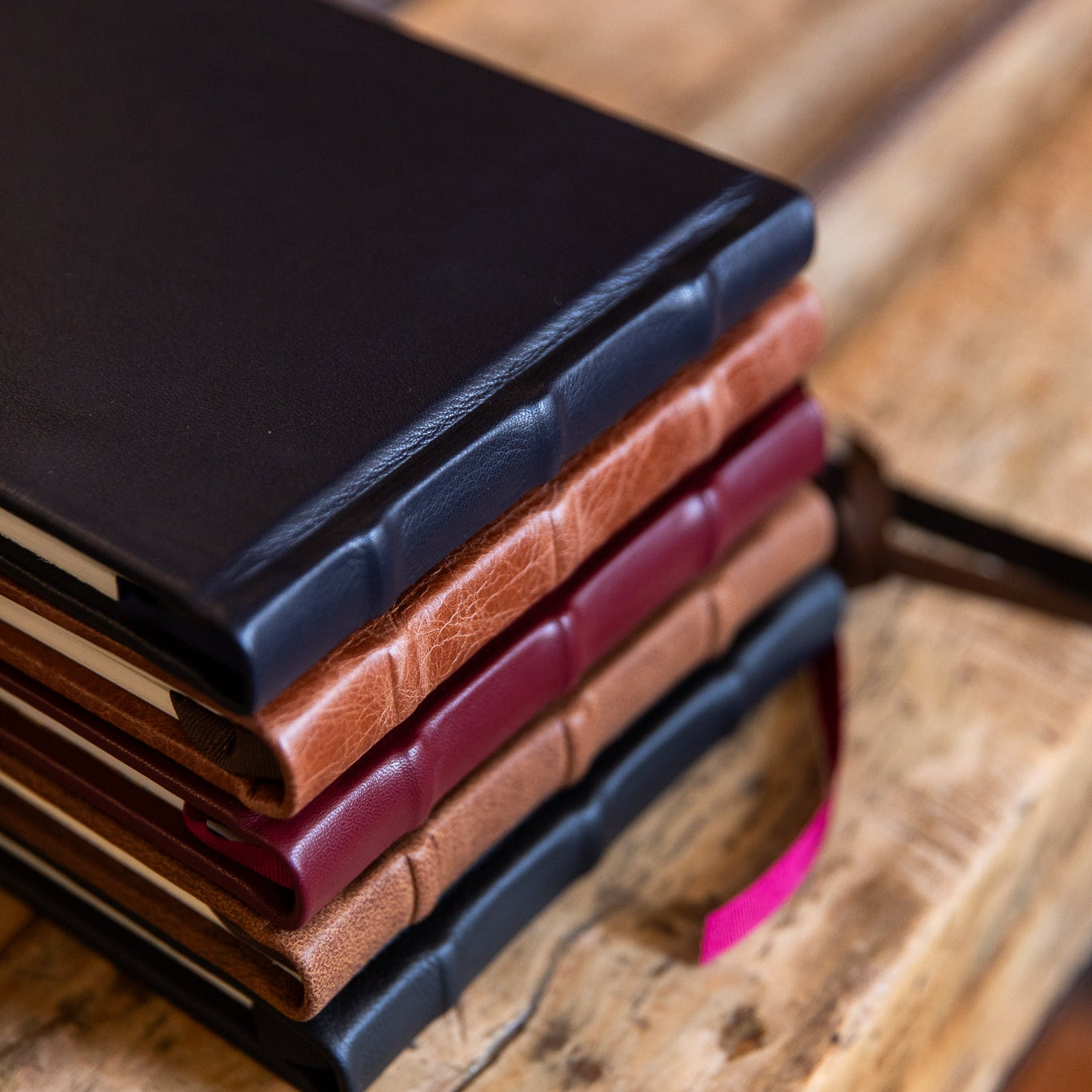 Stack of leather-bound signature books on a wooden surface