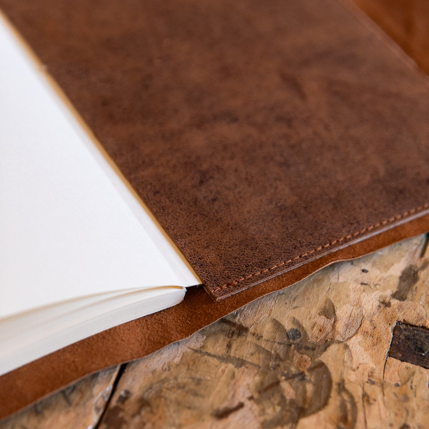 Close-up of a brown leather-bound journal pocket on a wooden surface