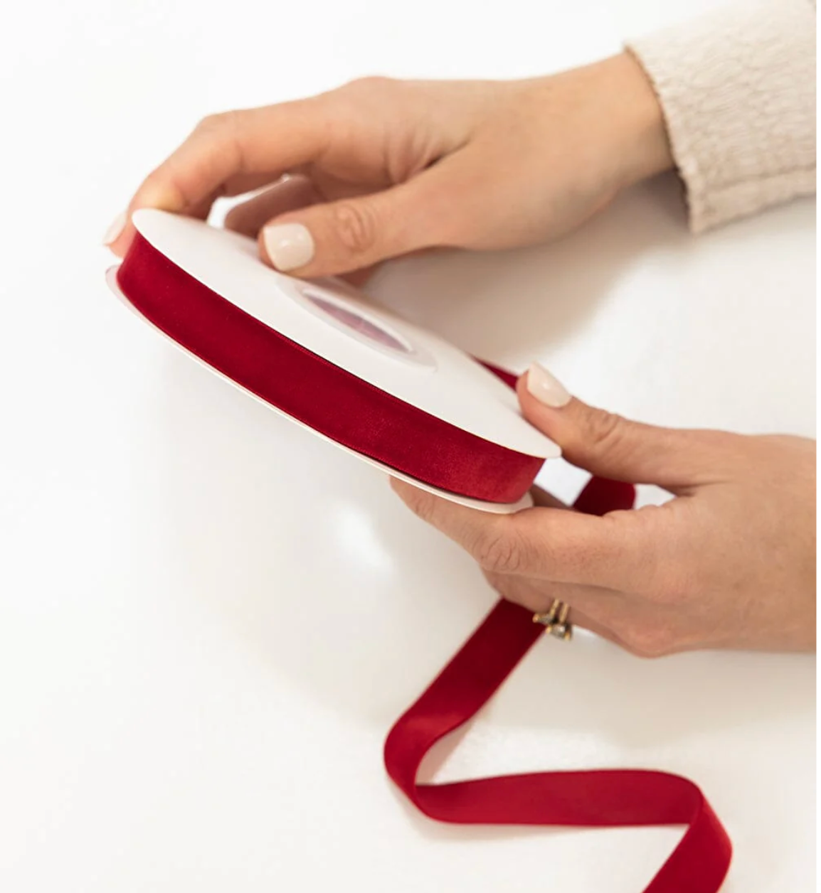 Red ribbon being held by hands on a white background