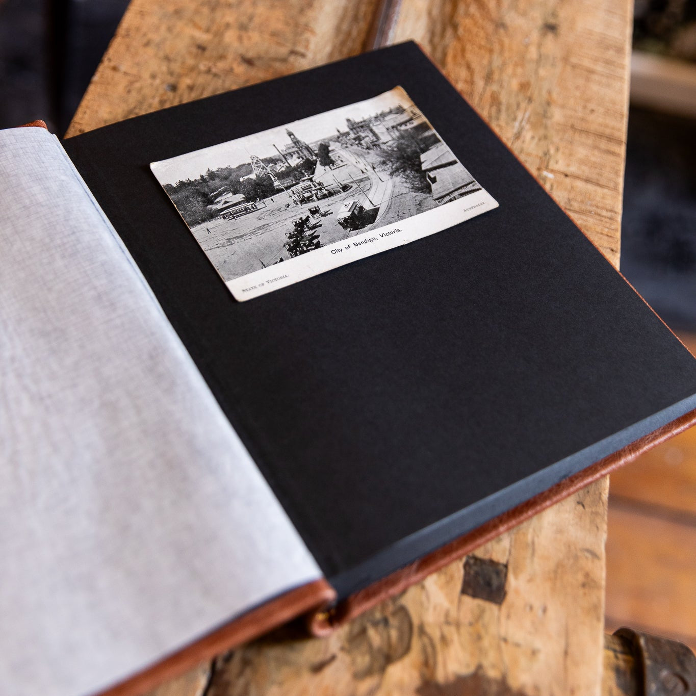 Open leather album with a black and white photo on a wooden surface