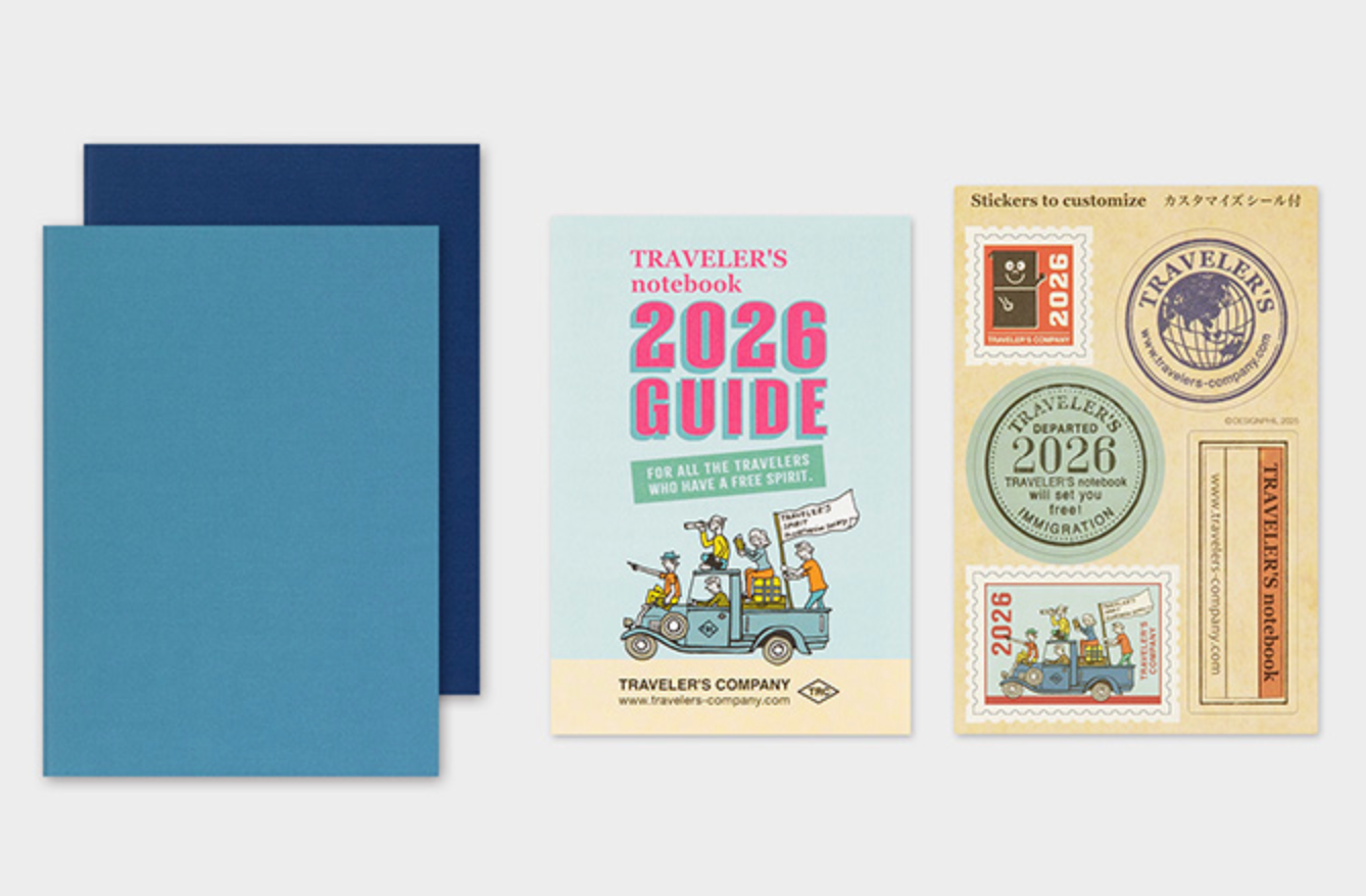 Traveler's notebook 2026 Guide with blue cover and colorful front cover featuring stamps and graphics.