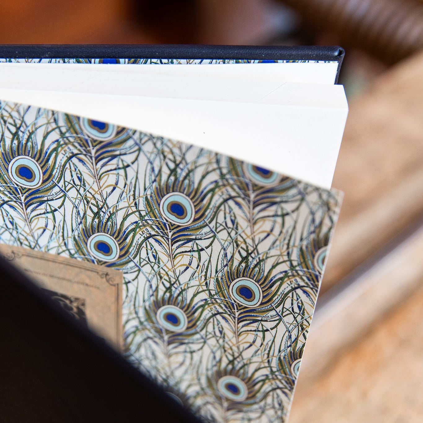 Peacock feather patterned paper with a wooden surface in the background