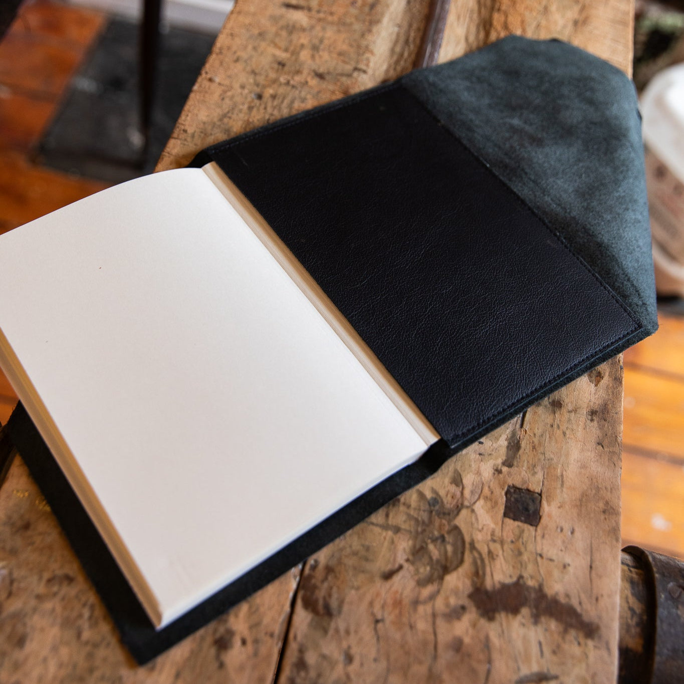 Open book with black cover on a wooden surface