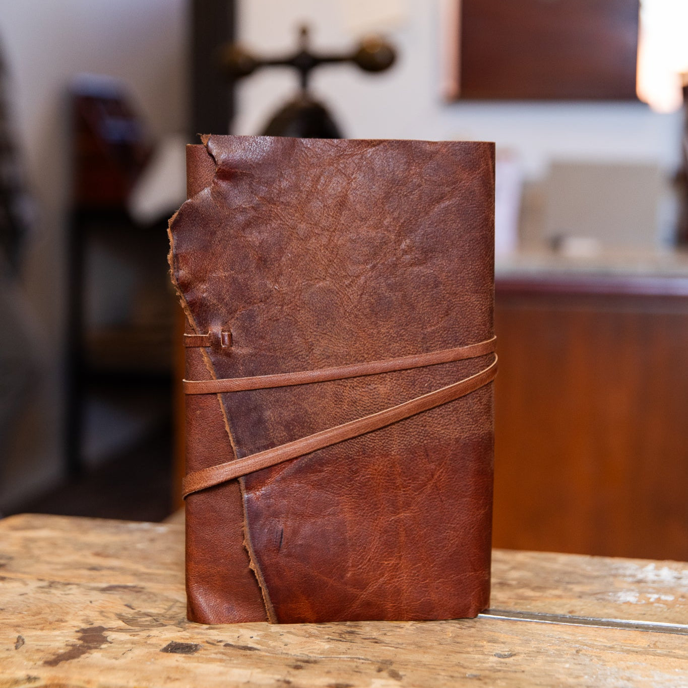 Brown leather notebook with a leather strap on a wooden surface