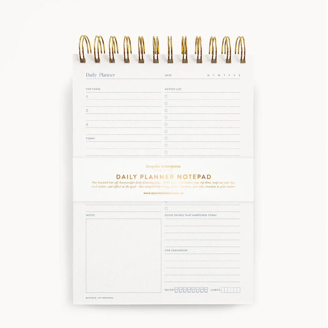 Daily planner notepad with gold spiral binding on a white background