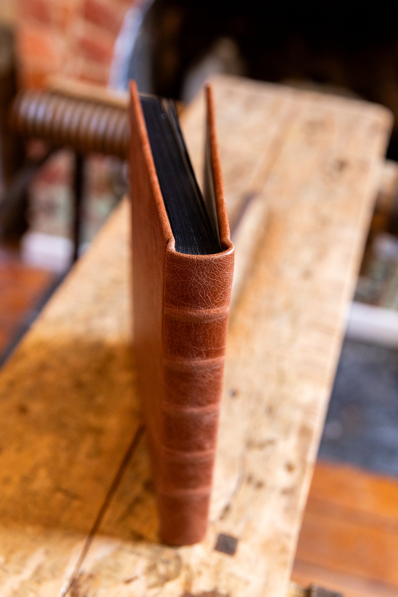 Close-up of a leather-bound album on a wooden surface with a blurred background