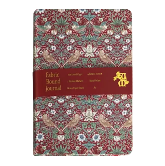 A fabric-bound journal with a red, green, and beige botanical pattern, wrapped in a dark red paper band with gold text and logo.