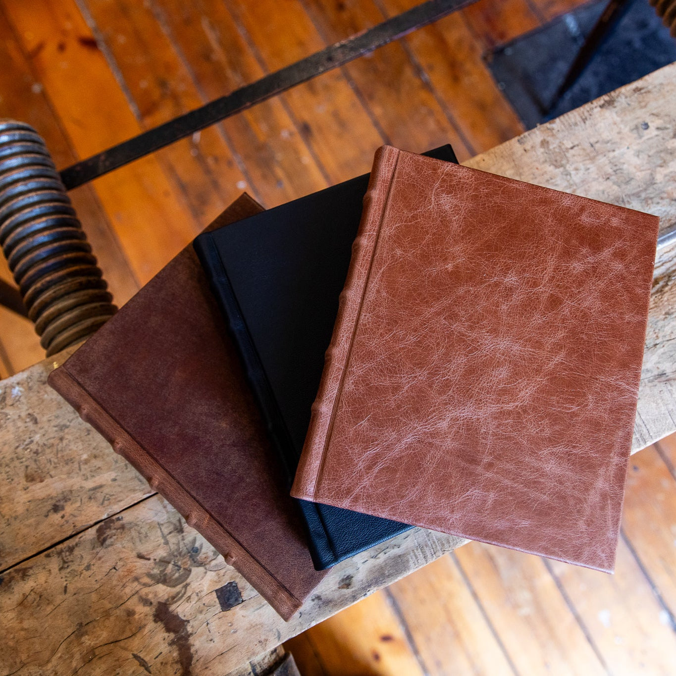 Three leather-bound photo albums on a wooden surface with a rustic background