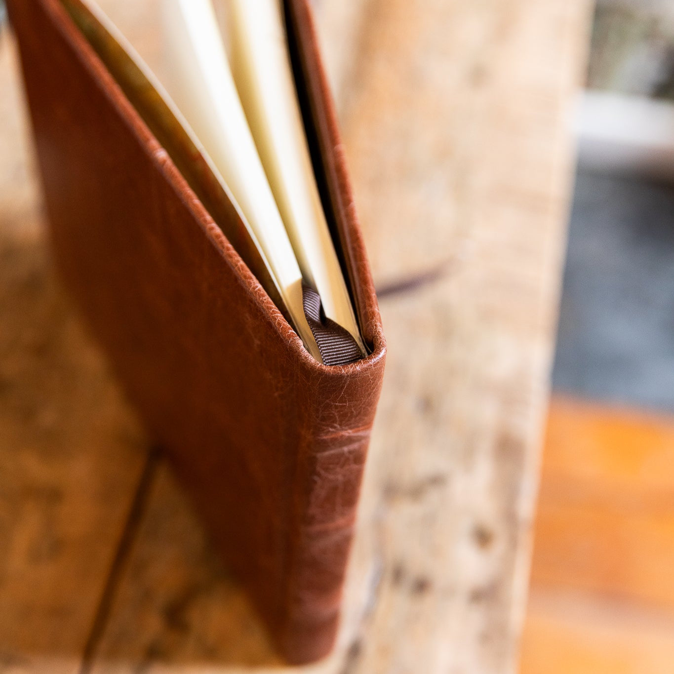 Brown leather guest book with a pen on a wooden surface