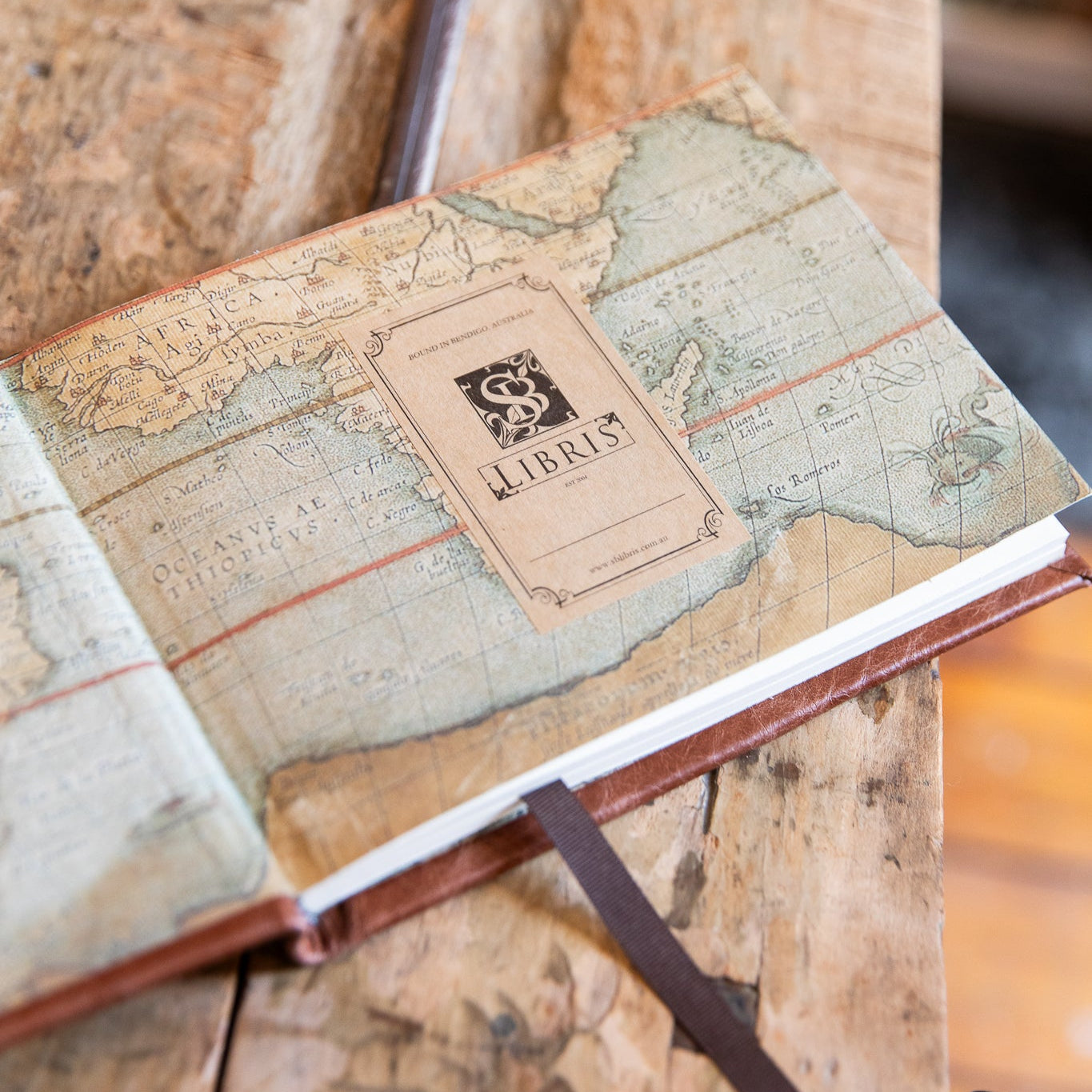 Vintage-map design endpapers and 'SB Libris' bookplate on a wooden surface