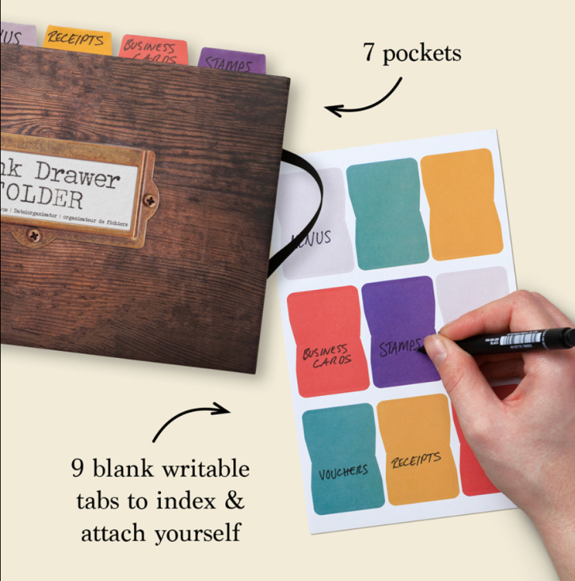 Wooden file folder with colorful labels and a hand writing on one of them, on a light background.