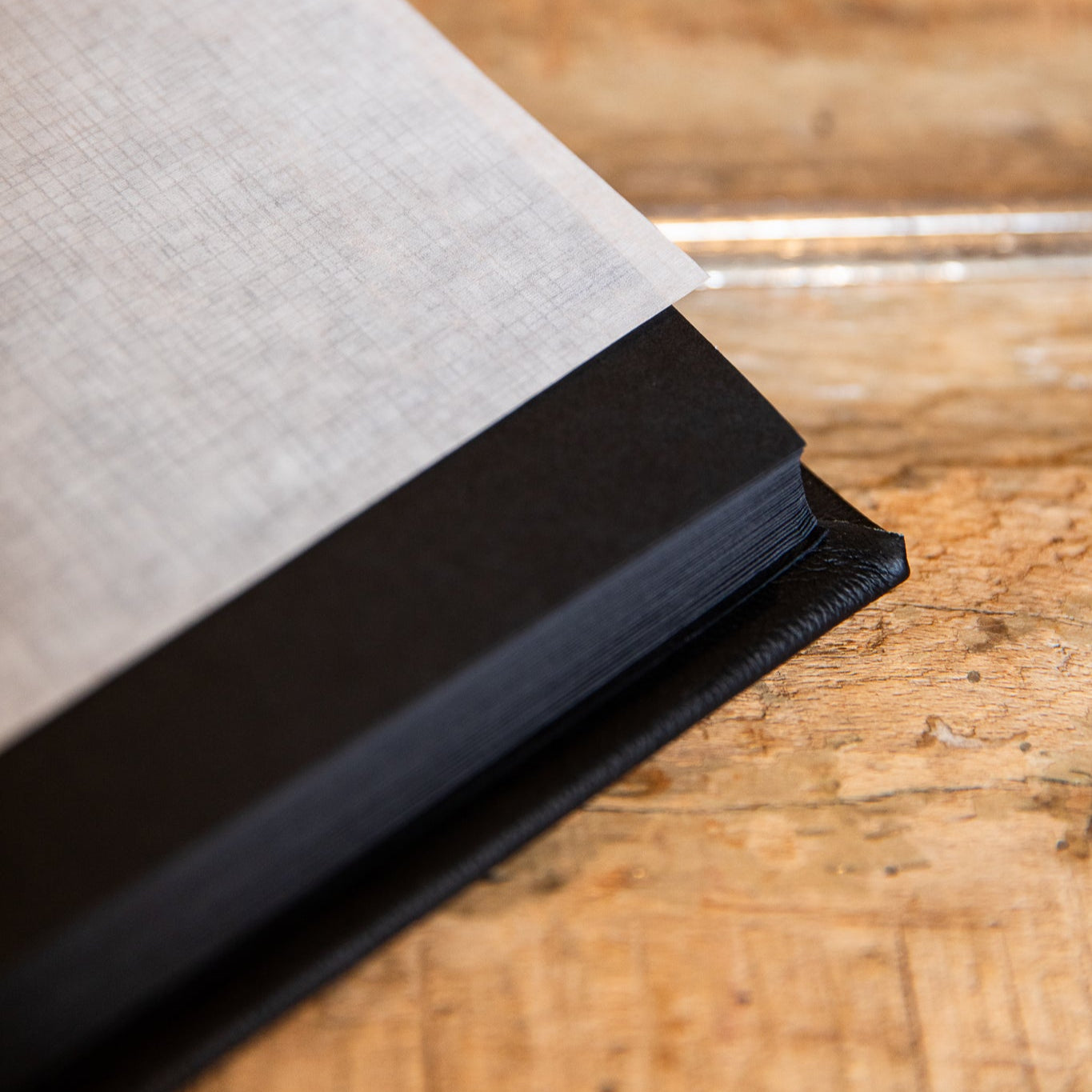 Close-up of a black leather album with textured cover on a wooden surface