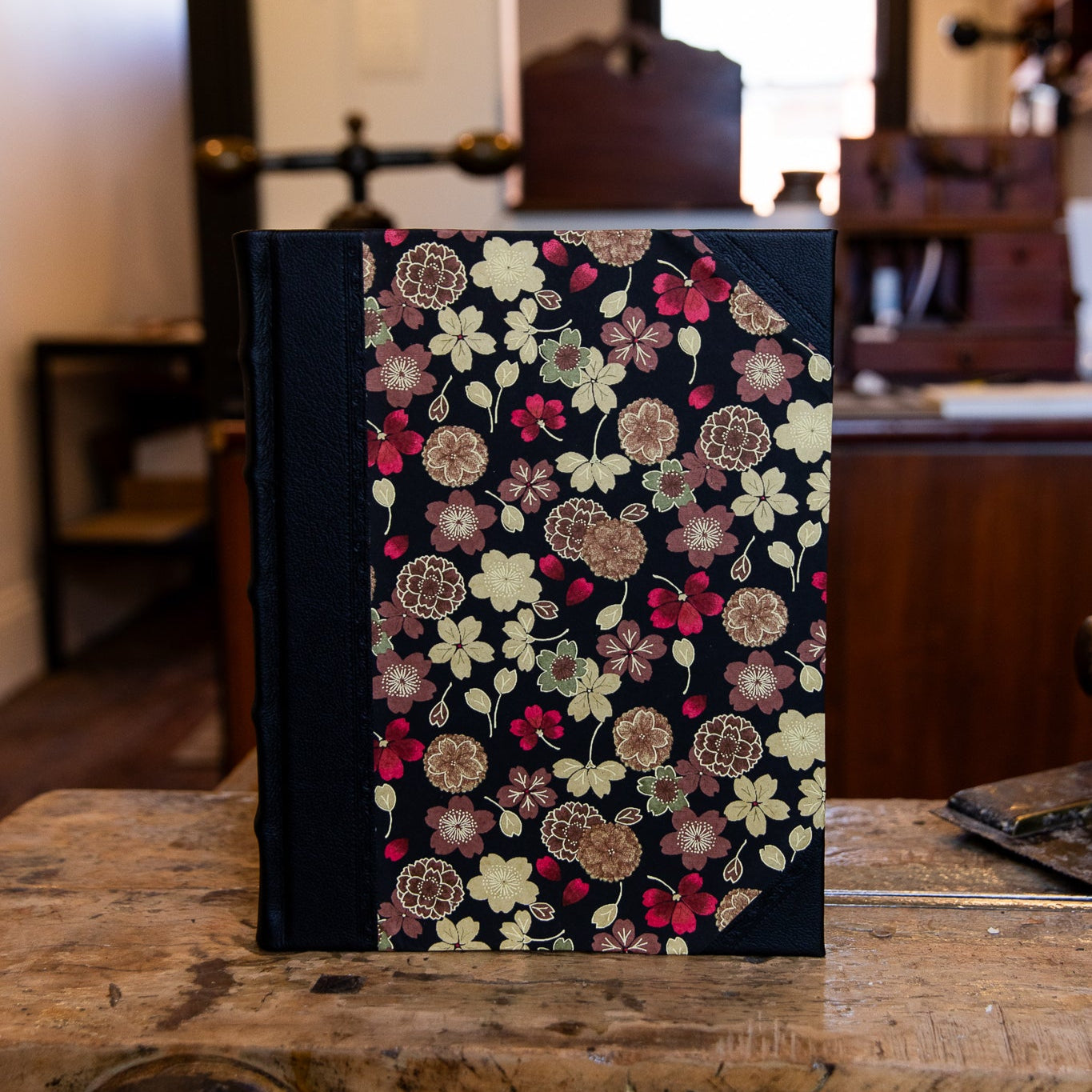 Front view of large handcrafted half leather journal by SB Libris featuring Japanese golden flower motif on black background.