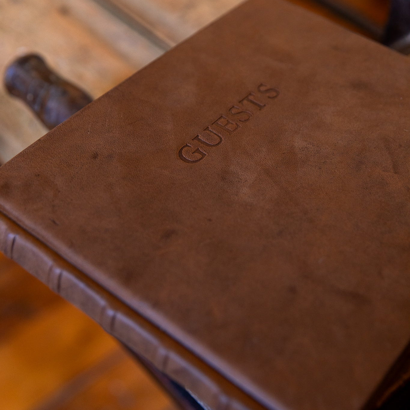 Close-up of the aged goatskin leather cover with “GUESTS” blind embossed, highlighting the soft texture and natural markings of the leather.