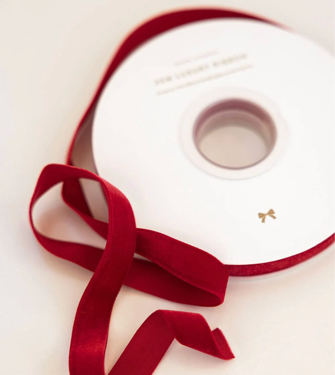 Red ribbon on a white spool with a brand name on a light background