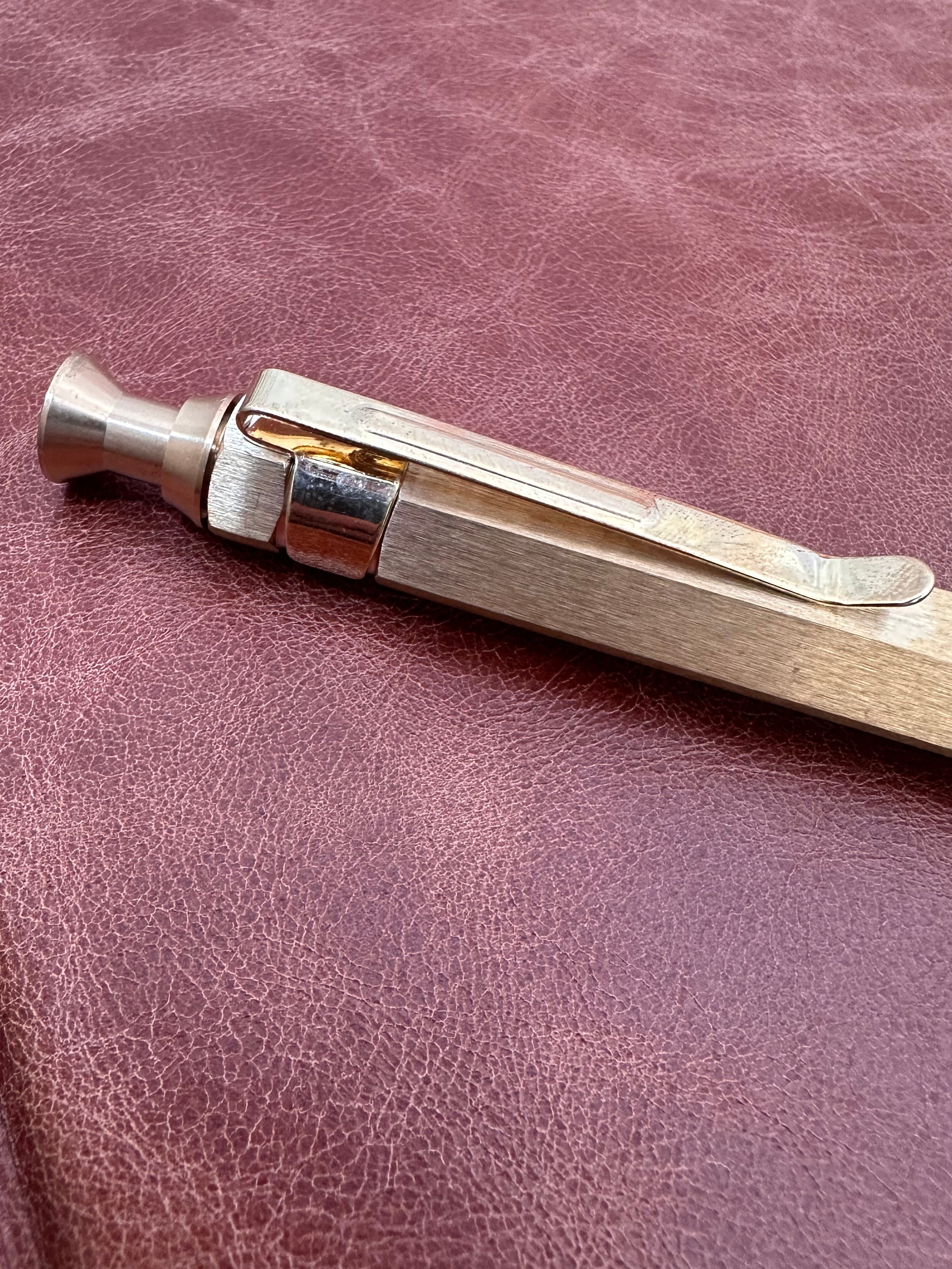 Metal pen on a brown leather surface