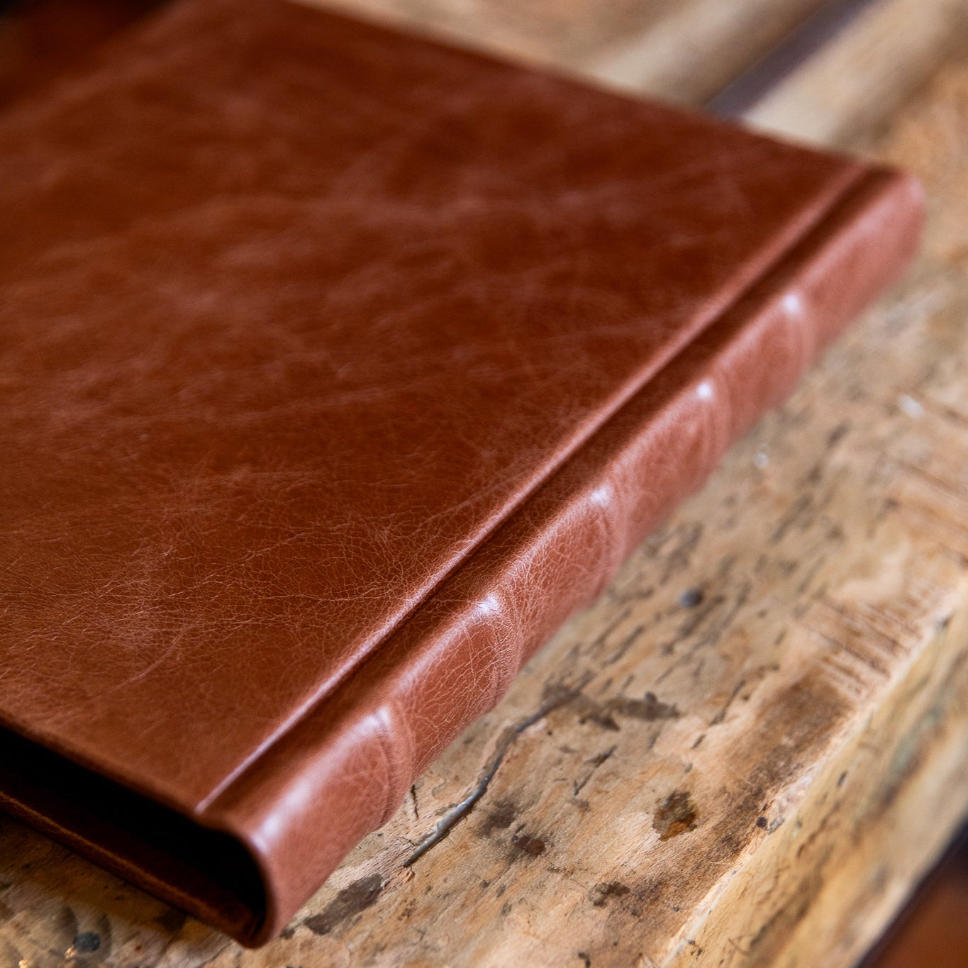 Brown leather photo album on a rustic wooden surface