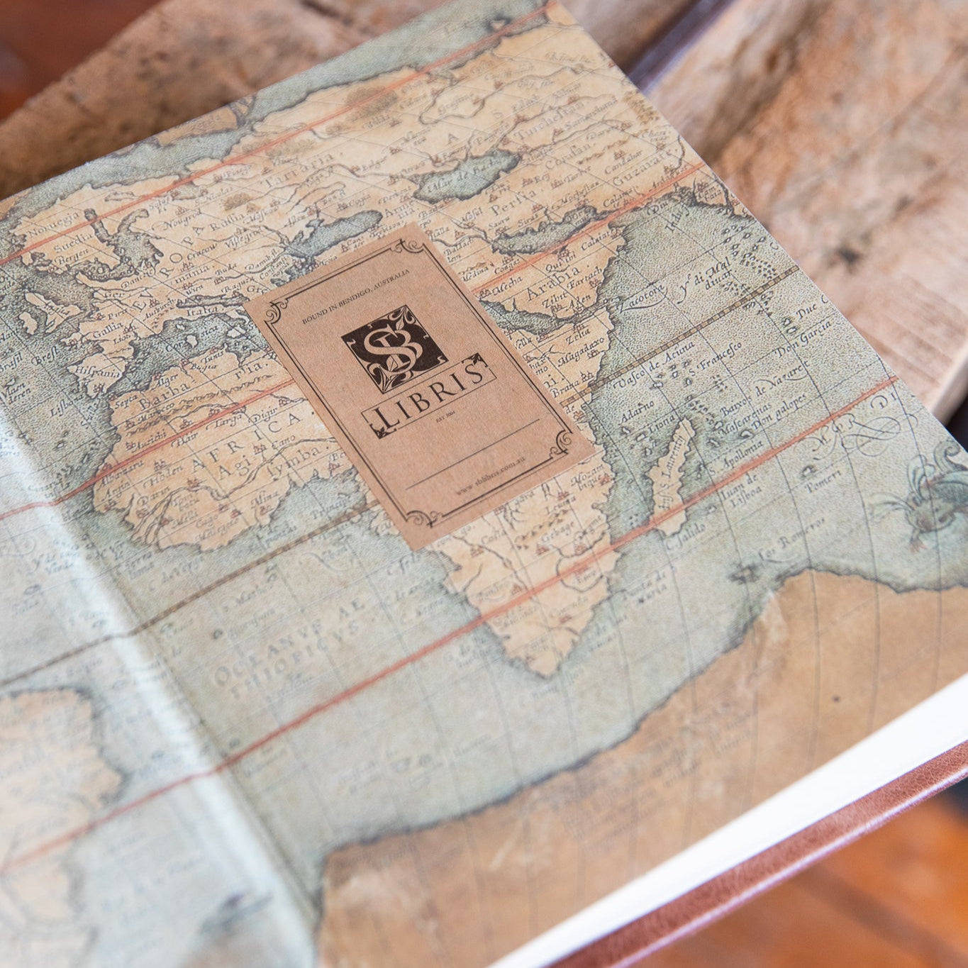 Vintage-style notebook with world map design on a wooden surface