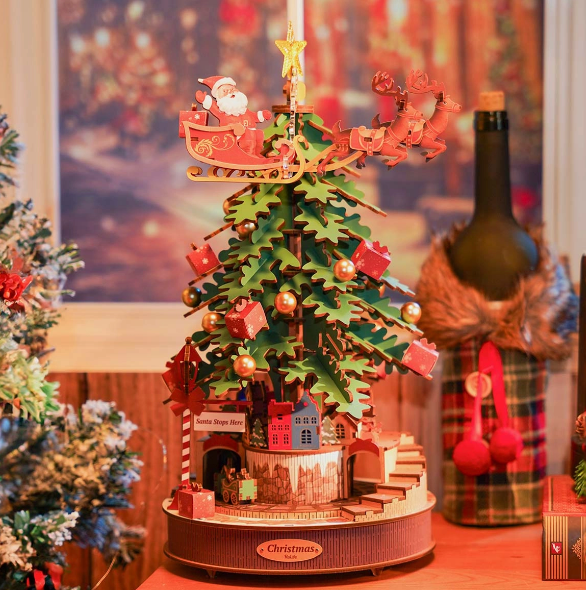 Decorative Christmas tree with Santa and reindeer on top, surrounded by festive decorations.