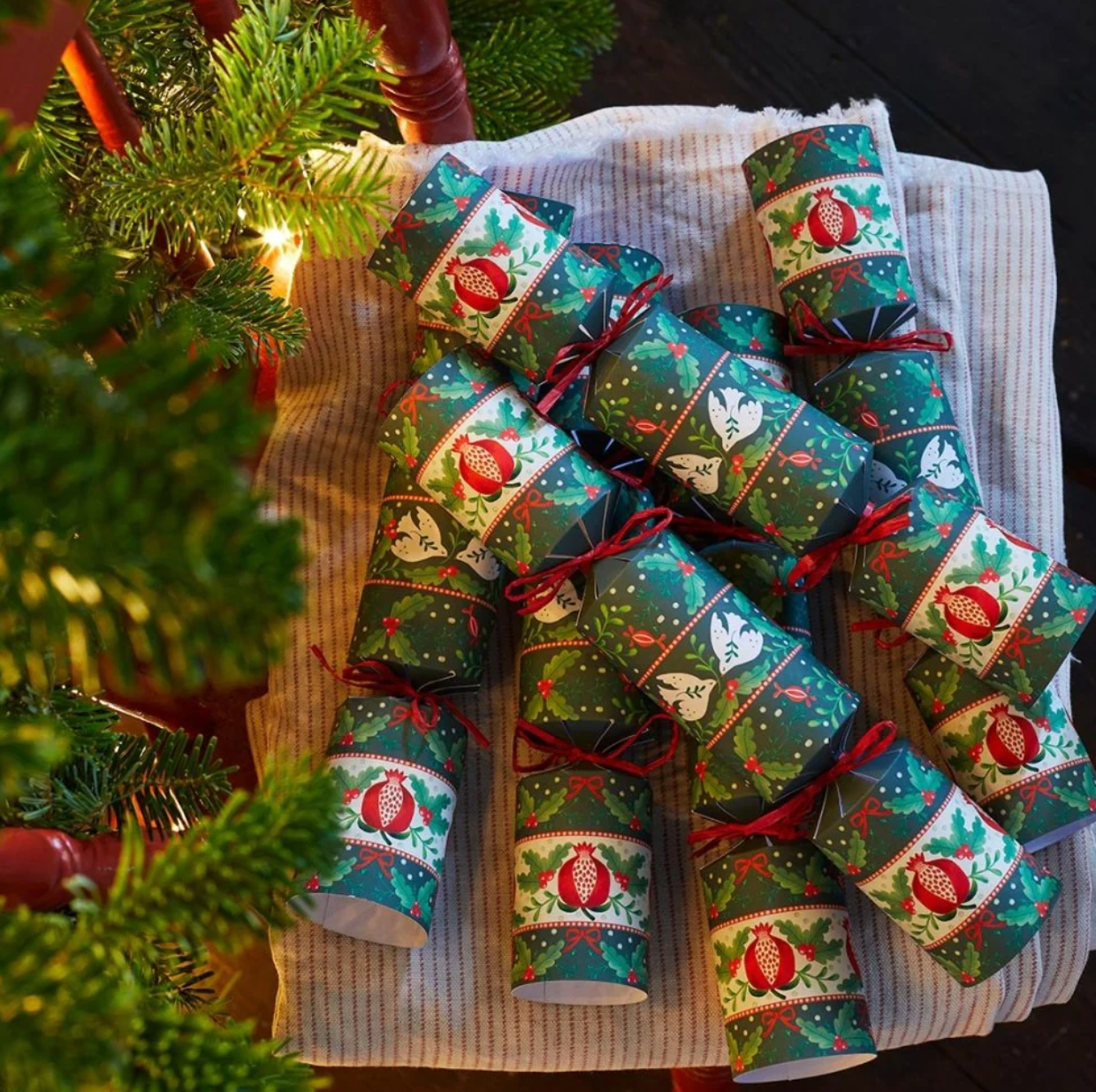 Decorative Christmas crackers on a table with a Christmas tree in the background