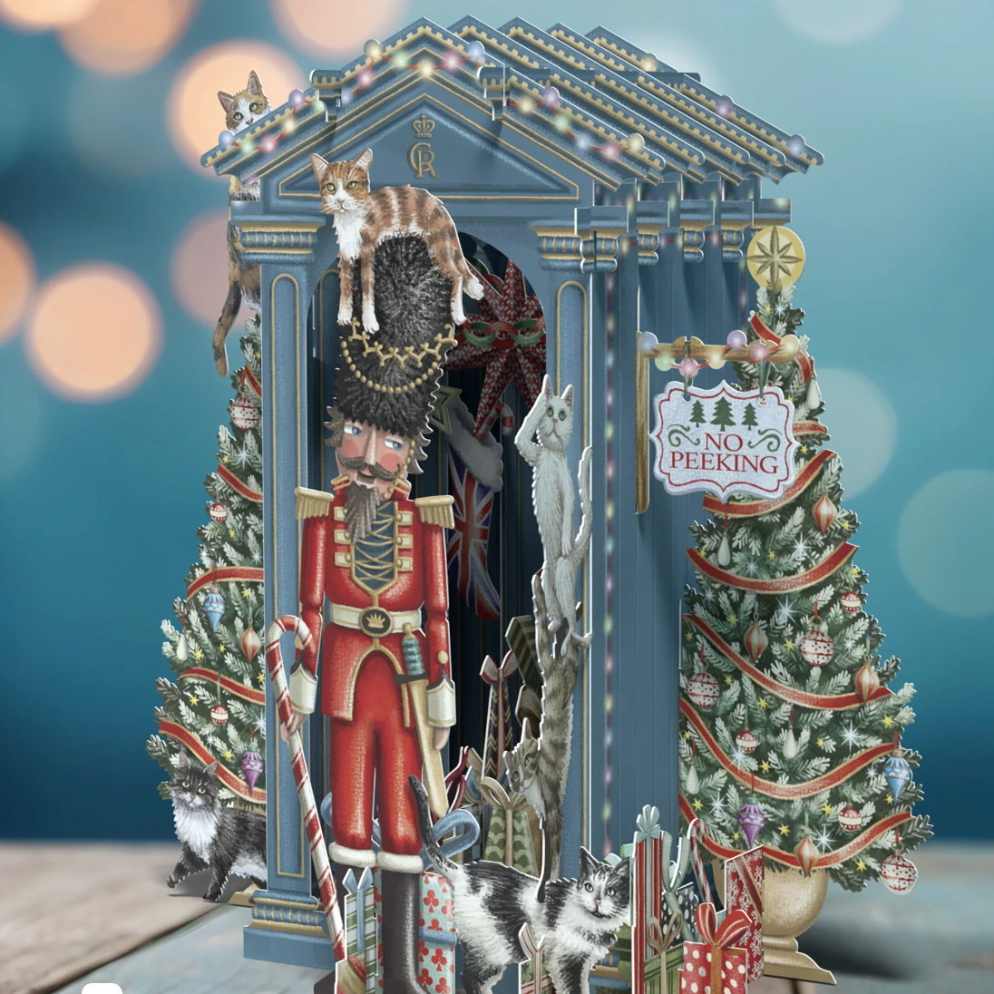 Decorative Christmas scene with a Nutcracker, trees, and cats against a blurred background.